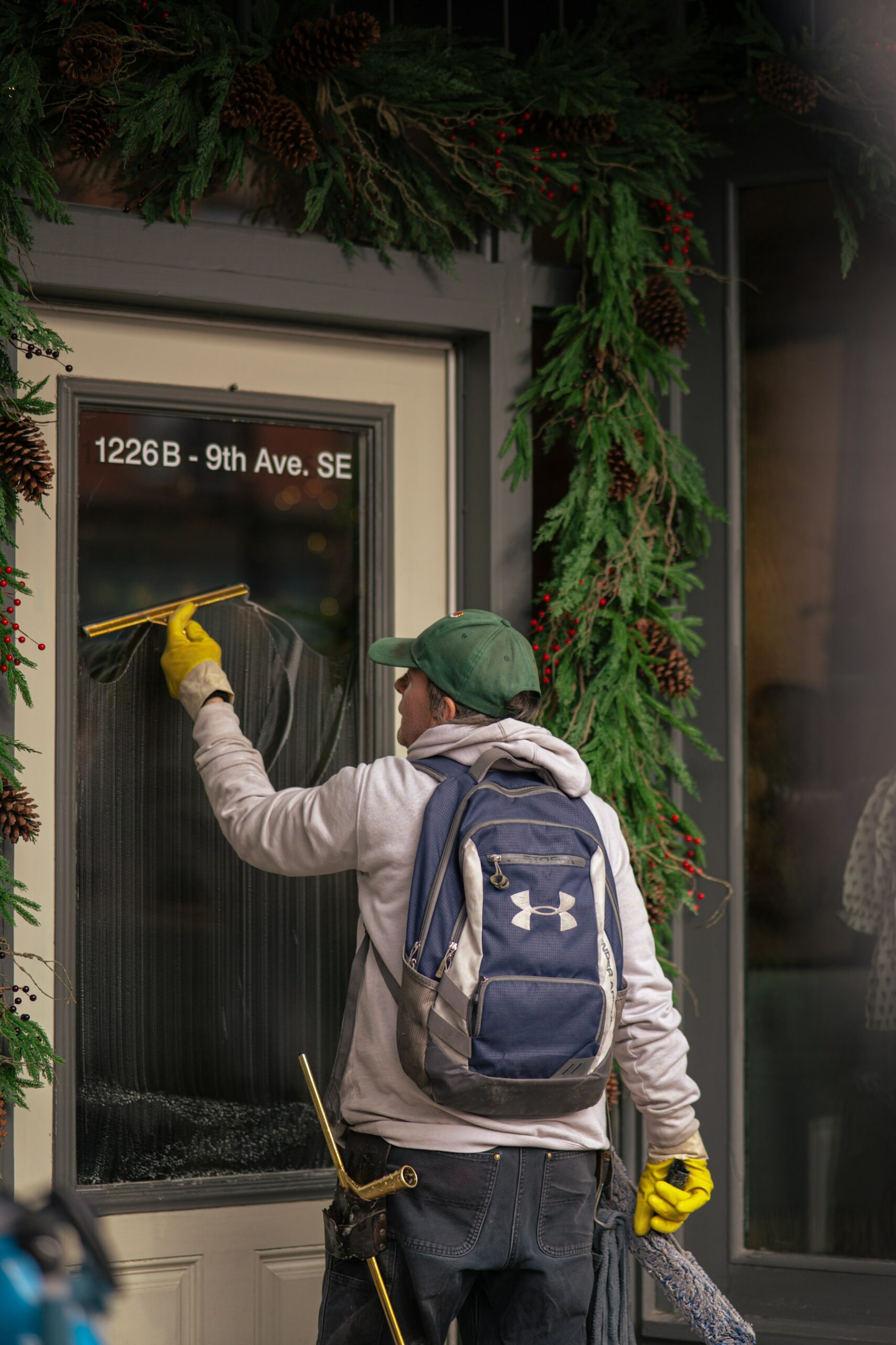Glasreiniger zieht eine Ladentür mit dem Fensterwischer ab