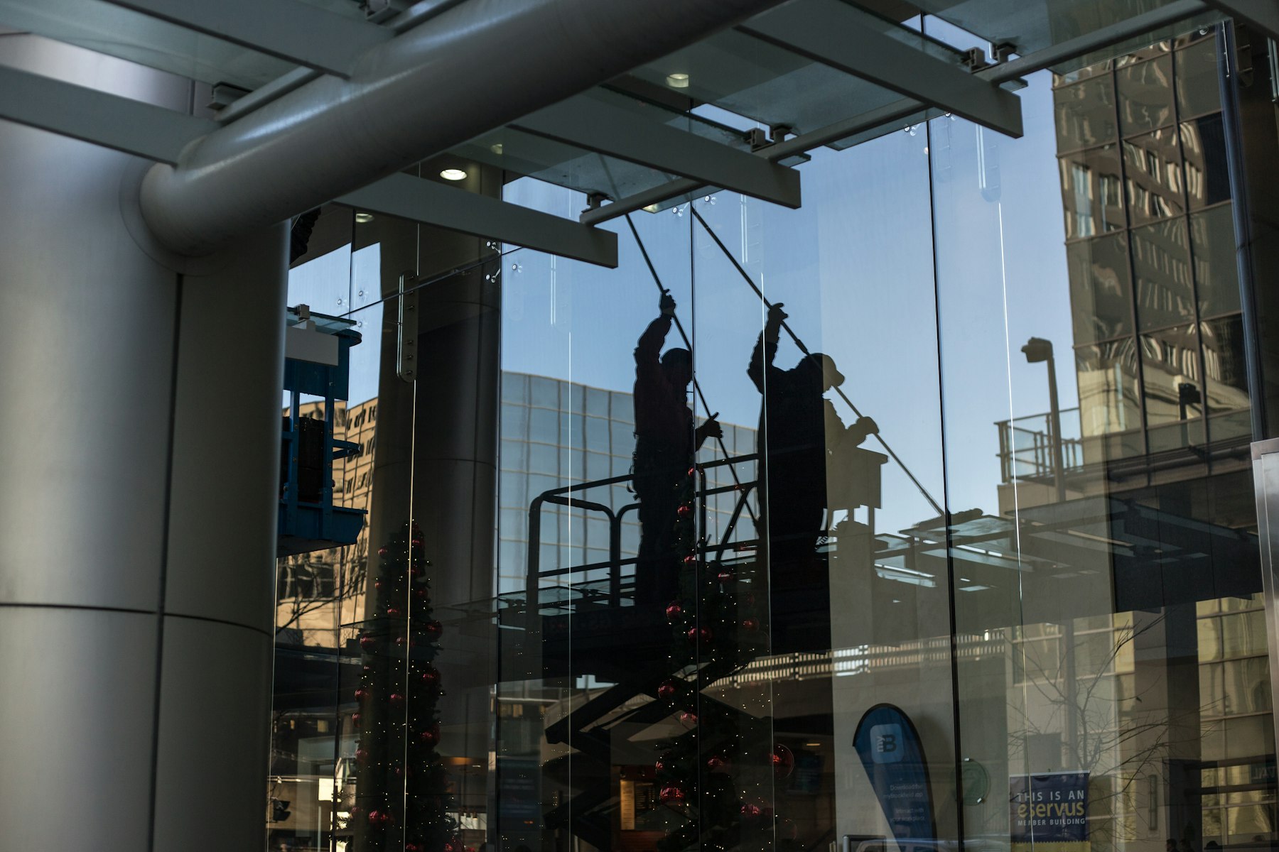 Glasreiniger auf einer Hebebühne vor einer großen Glasfront