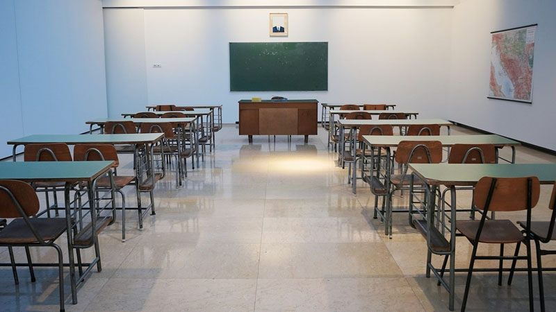 Leeres, aufgeräumtes Klassenzimmer mit Tischen und Tafel